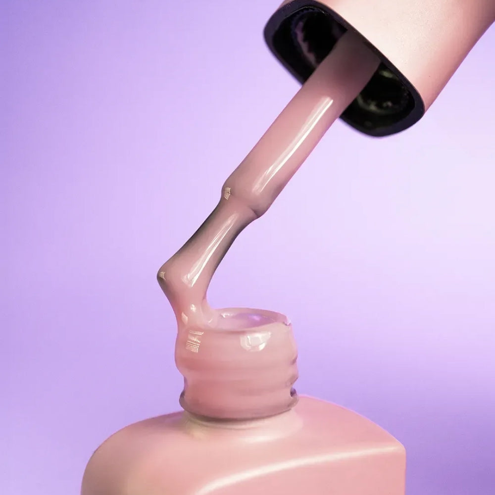 Nail technician applying DNKa Cover Base #0007 Powerful to a natural nail
