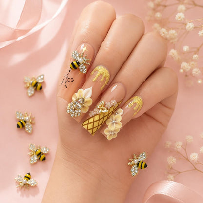 Each bee features a gold-tone frame, sparkling crystal wings, black and yellow enamel details, and a pearl accent for an elegant jewelry-inspired finish.