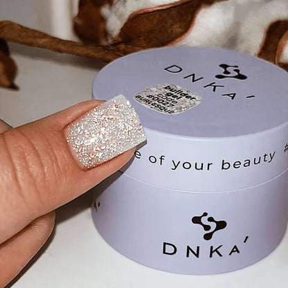 DNKa Builder Gel #0027 Burlesque — swatch on nail tip, silver glitter shimmer
