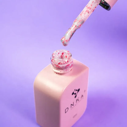 Nail technician applying DNKa Cover Base #0010A Lovely to a natural nail