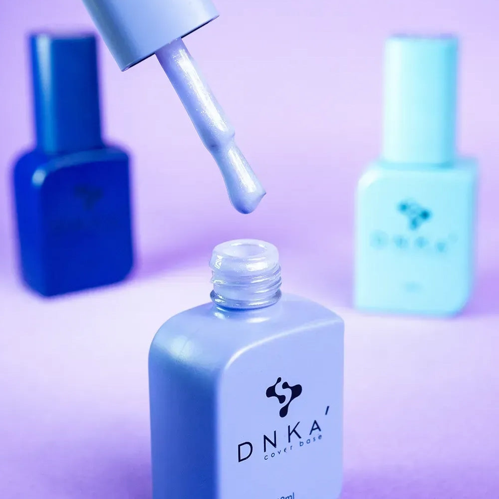 Nail technician applying DNKa Cover Base #0015 Cosmic to a prepped nail plate