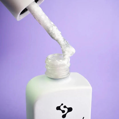 Open 30ml Lotus bottle with brush resting against the cap, white gel with color flecks on the bristles