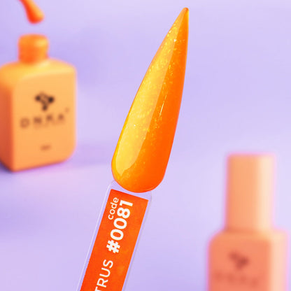 Macro shot of Citrus gel on a nail tip — bright orange base, individual glitter particles catching light