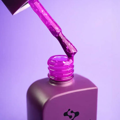 Single nail close-up showing Courage's texture — smooth violet gel interrupted by flecks of gold