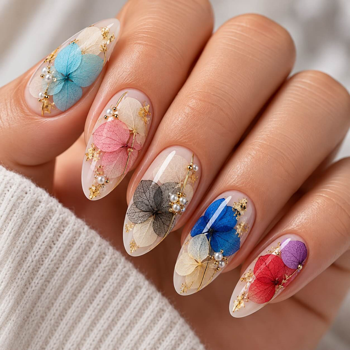 Nail art with a gray dried petal, pearls and gold details