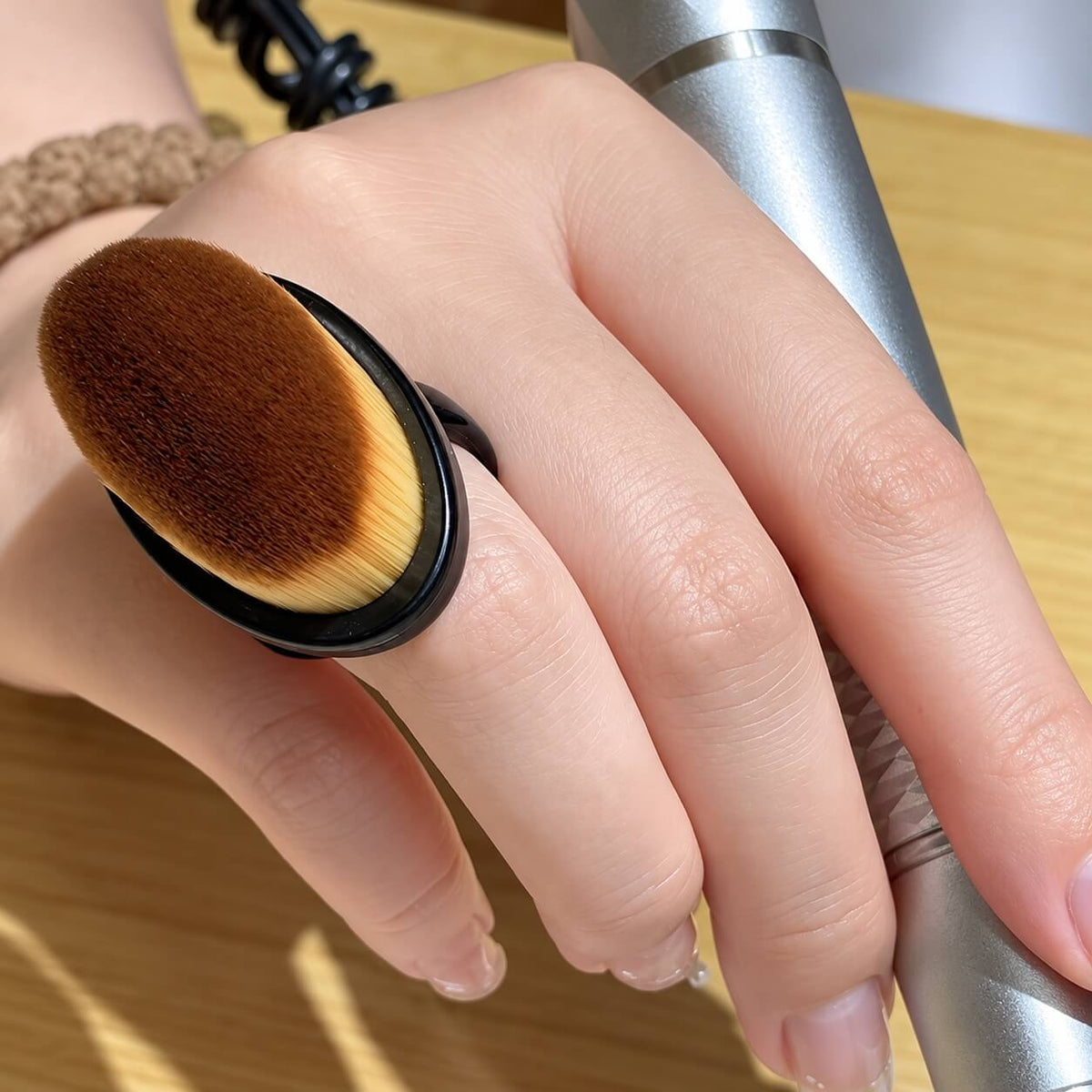 Round, soft bristle head of a nail dust brush with finger loop handle